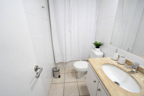 een witte badkamer met een wastafel en een toilet bij La Serena - Departamento Frente al Mar in La Serena