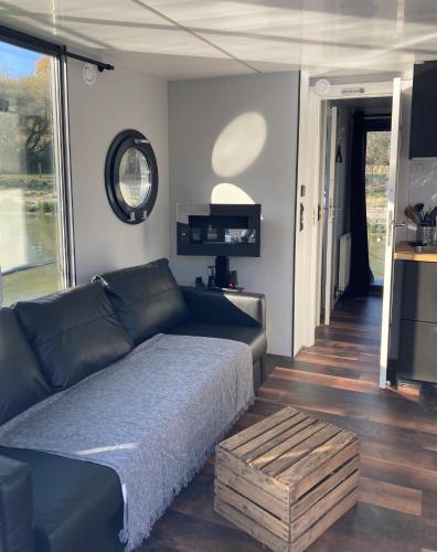 un salon avec un canapé noir et une table dans l'établissement Ecolodge Charles Ashton Hébergement insolite sur l'eau, à Sarzeau