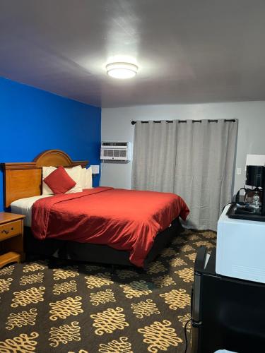 1 dormitorio con 1 cama con manta roja y paredes azules en Midway Motel, 