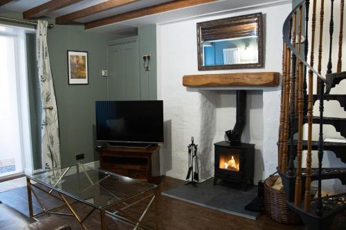 een woonkamer met een open haard en een televisie bij The Burrow in Kelso