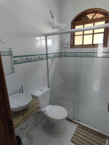 Baño blanco con aseo y lavamanos en Recanto de Araruama, en Araruama