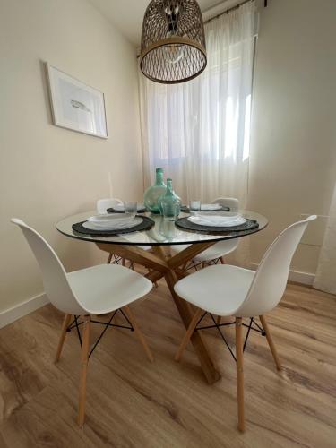 a dining room with a glass table and white chairs at Apartamento Córboba Centro in Córdoba