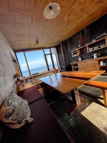 a room with a wooden table and a large window at El Coo Lodge in Queilén