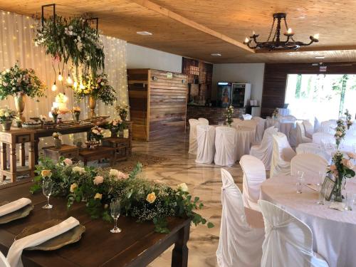 a room with white tables and white chairs and flowers at Sítio novo pousada in Piratuba