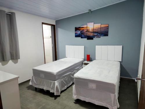 2 łóżka w pokoju z niebieskimi ścianami w obiekcie Aloha Casa em Ilhabela w mieście Ilhabela