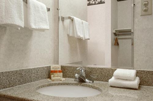 a bathroom with a sink and a mirror and towels at Travelodge by Wyndham Ridgeway Martinsville Area in Martinsville