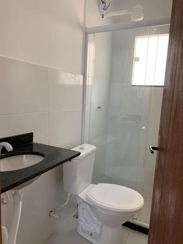 a white bathroom with a toilet and a sink at Lavínia loft 2 in Búzios