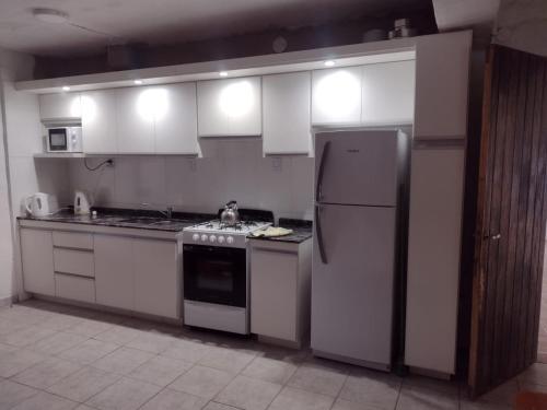 a kitchen with white cabinets and a refrigerator at El Abuelo in Santa Rosa de Calamuchita