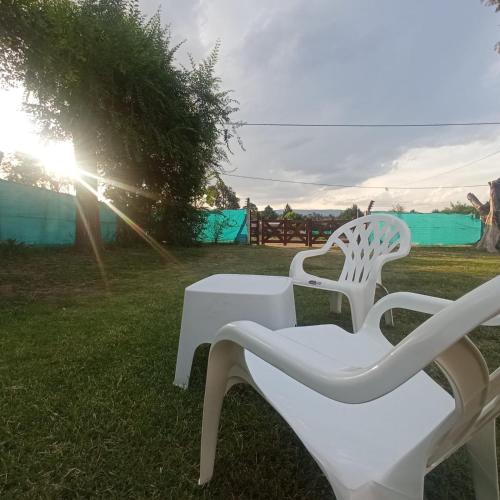 dos sillas blancas y una mesa en el césped en El Abuelo en Santa Rosa de Calamuchita