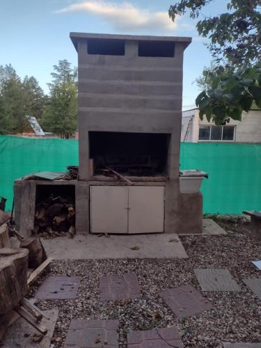 una chimenea en un patio trasero con una valla verde en El Abuelo en Santa Rosa de Calamuchita