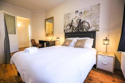 - une chambre avec un lit blanc et un vélo sur le mur dans l'établissement Le 34 Malon, T5 hypercentre chic et cosy, wifi, netflix par SOVALFI, à Saint-Étienne