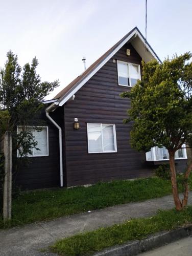 a black house with white windows and trees at Casa de la Ribera Pelantaro in Valdivia