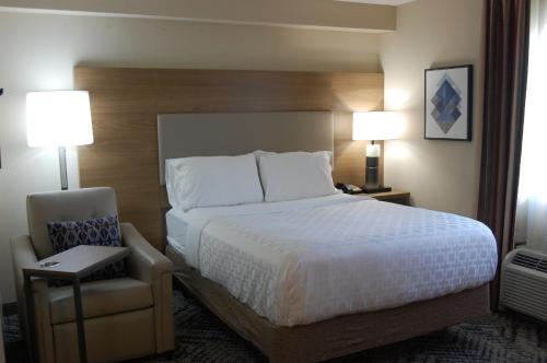 a bedroom with a bed and a chair and two lamps at Candlewood Suites Harrisburg I-81 Hershey Area by IHG in Harrisburg