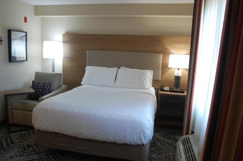 a hotel room with a large bed and a chair at Candlewood Suites Harrisburg I-81 Hershey Area by IHG in Harrisburg