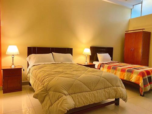 a bedroom with two beds and two lamps in it at Hotel Las Palmeras in Huacho