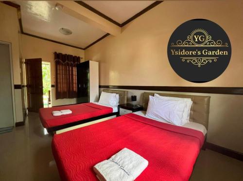 2 Betten in einem Zimmer mit roter Bettwäsche in der Unterkunft YSIDORE'S GARDEN in Roxas