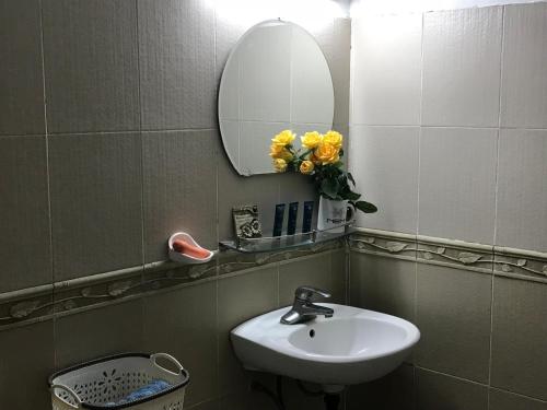 a bathroom with a sink and a mirror and yellow flowers at 105 Láng Hạ in Hanoi