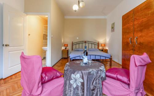 a bedroom with a bed and a table with pink chairs at Liznjan - Blue Gate Manor in Ližnjan