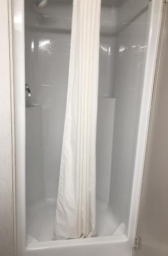 a shower with a white shower curtain in a bathroom at Days Inn by Wyndham Niagara Falls Centre St By the Falls in Niagara Falls
