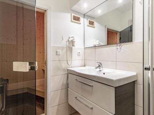 La salle de bains blanche est pourvue d'un lavabo et d'une douche. dans l'établissement Two-Bedroom Holiday home in Wendtorf 1, à Wendtorf