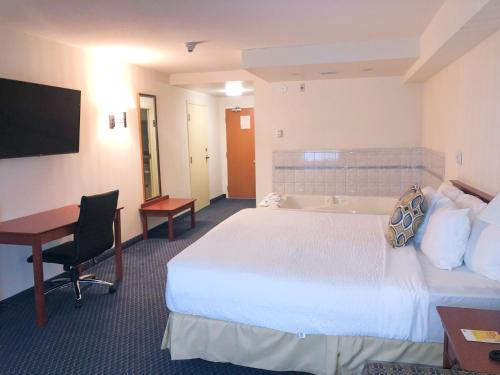 a hotel room with a bed and a desk and a tub at Days Inn by Wyndham Niagara Falls Centre St By the Falls in Niagara Falls