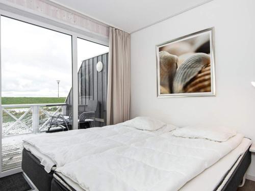 a white bedroom with a bed and a balcony at Two-Bedroom Holiday home in Wendtorf 6 in Wendtorf
