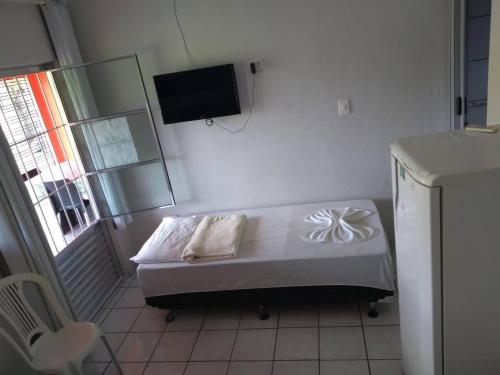 a small bedroom with a bed and a television at Pousada da Sônia in Camaragibe