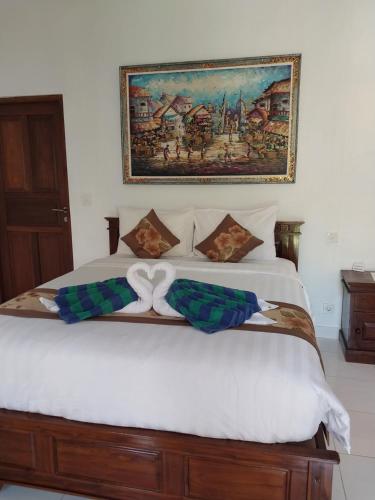 a bedroom with a large white bed with a painting on the wall at Isola D'oro lembongan in Nusa Lembongan