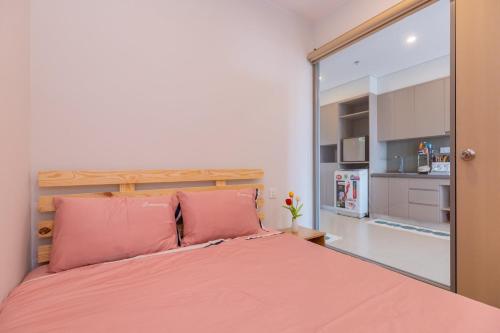 a bedroom with a bed with pink pillows and a mirror at Căn hộ Studio The Sóng Vũng Tàu in Vung Tau