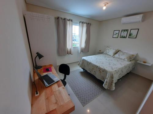 een slaapkamer met een bed en een laptop op een tafel bij Apartamento Novo Norte da Ilha in Florianópolis