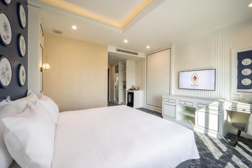 a bedroom with a large white bed and a desk at Eastin Hotel Vientiane in Vientiane