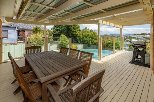a deck with a wooden table and chairs and a grill at 36 Churchill in Forster
