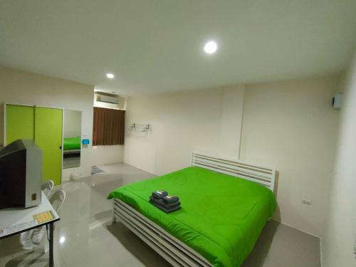 Habitación hospital con cama verde y TV en Sorworakit Hotel, en Bang Saen