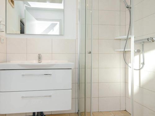 a white bathroom with a sink and a shower at Holiday Home Strandblick II in Wendtorf