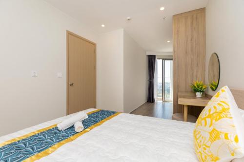 a bedroom with a large white bed with yellow and blue pillows at Căn hộ Studio The Sóng Vũng Tàu in Vung Tau
