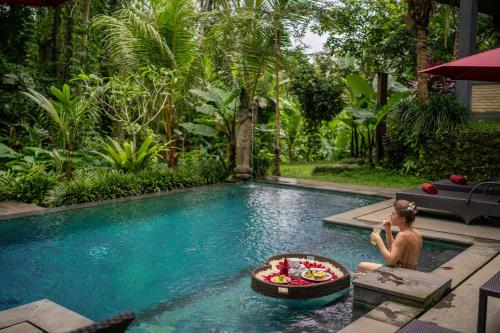 a man sitting in a pool with a bowl of fruit at Villa Ubud Sunshine in Ubud