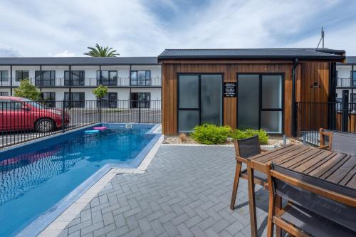 a house with a swimming pool and a building at ASURE Rotorua International Motor Inn in Rotorua
