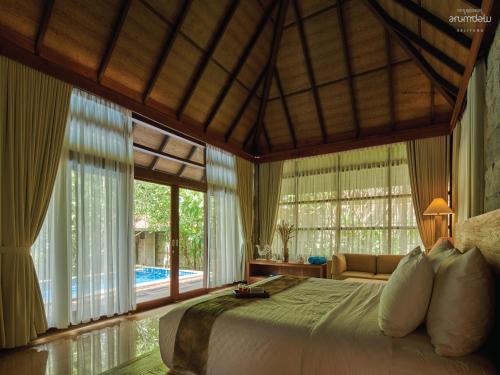 a bedroom with a large bed in a room with windows at Arumdalu Private Resort in Membalong