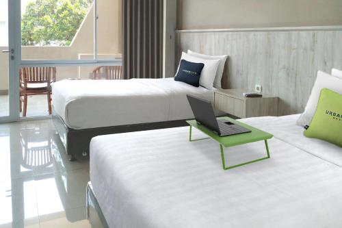 une chambre d'hôtel avec deux lits et un ordinateur portable sur une table dans l'établissement Urbanview Hotel Rio Life House Cianjur by RedDoorz, à Cianjur