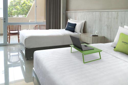 a hotel room with two beds and a laptop on a table at Urbanview Hotel Rio Life House Cianjur by RedDoorz in Tjiandjur