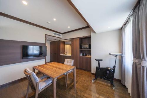 a dining room with a table and chairs and a television at The Saihokukan Hotel in Nagano