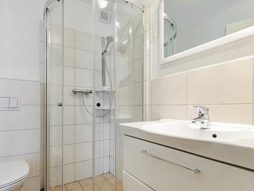 a white bathroom with a sink and a shower at Holiday Home Strandblick IV in Wendtorf