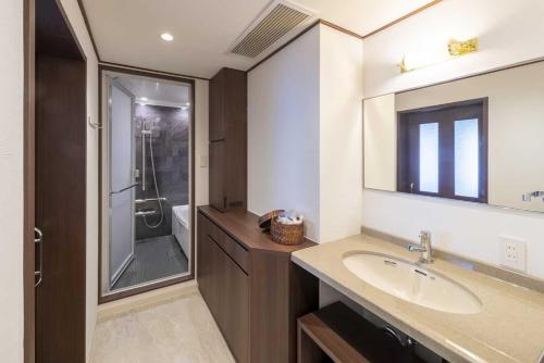 uma casa de banho com um lavatório e um chuveiro em The Saihokukan Hotel em Nagano
