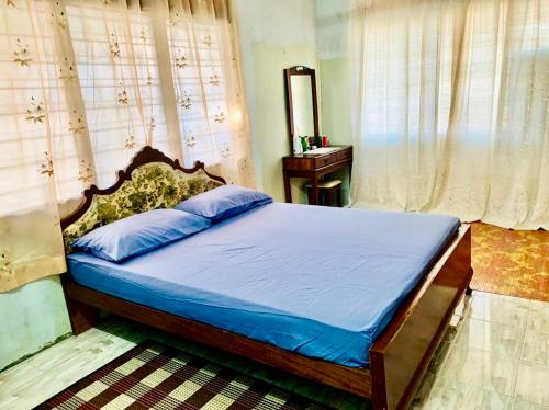 a bedroom with a bed with blue sheets and a mirror at Ramizu Homestay Pokok Sena in Pokok Sena