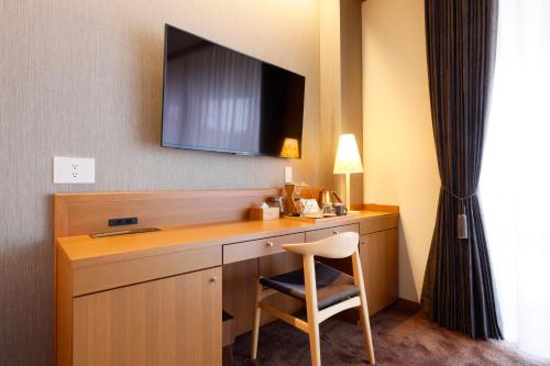 a desk in a hotel room with a chair and a television at Hotel Nara Sakurai No Sato in Sakurai