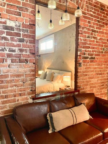 a leather couch in front of a brick wall with a mirror at Oxford on Otho in Inverell