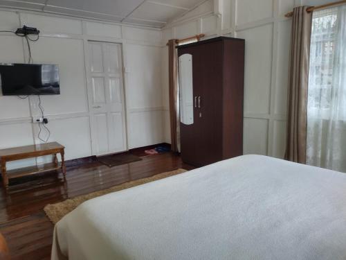 a bedroom with a bed and a cabinet and a television at Casa Encanto Homestay in Shillong