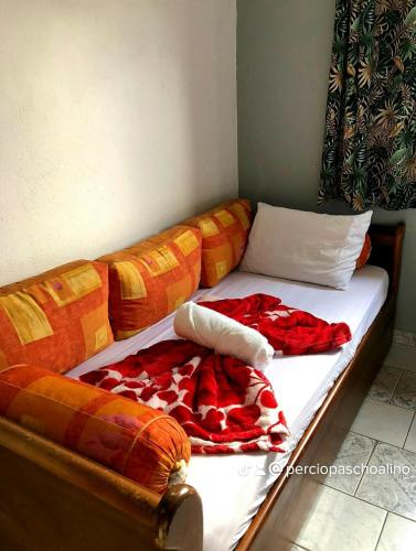 a bed with two blankets on it with a couch at Pousada Aconchego Bertioga in Bertioga