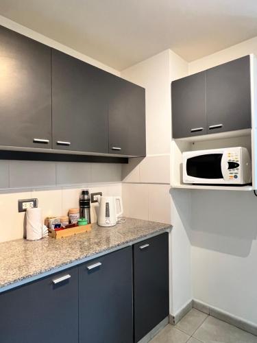 a kitchen with black cabinets and a microwave at Locación Jujuy in San Salvador de Jujuy