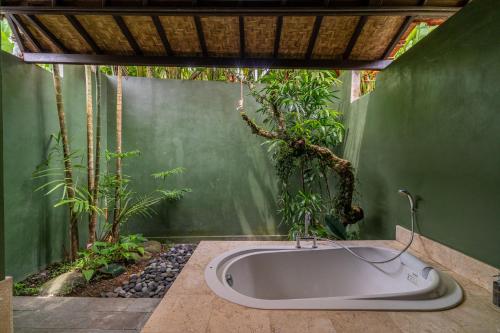 a bath tub in a room with plants at Villa Ubud Sunshine in Ubud